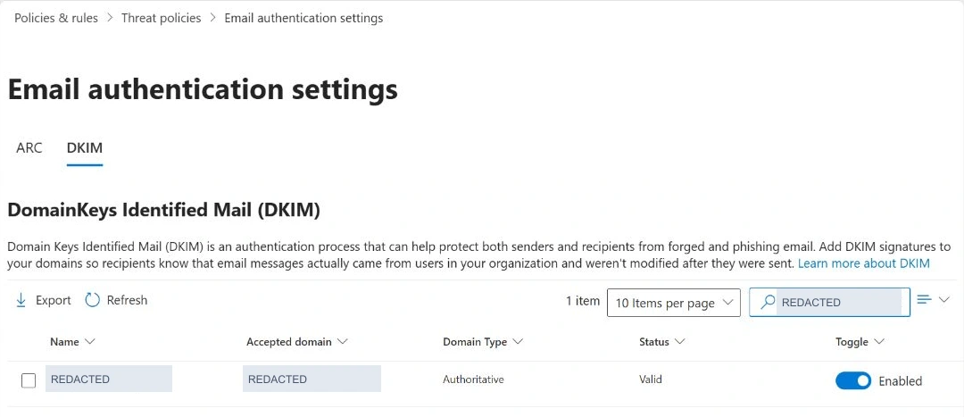 Microsoft Defender DKIM list showing an anonymized domain with Valid status and Enabled signing.
